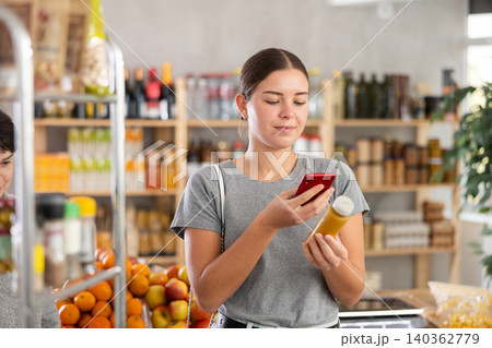 In shop youth girl scan QR code and take reading smoothie package bottle using phone camera In shop youth girl scan QR code and take reading smoothie package bottle using phone camera 140362779