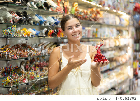 Female buyer holds in hands tests figurine she-dancer flamenco in memorable gifts shop 140362802
