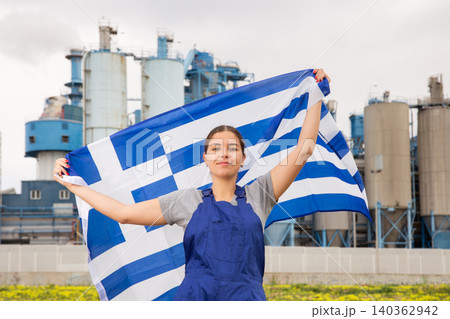 Smiling young woman near factory with Greece flag Smiling young woman near factory with Greece flag 140362942