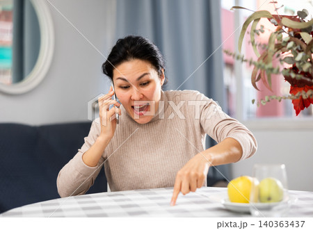 Angry woman arguing while having telephone conversation Angry woman arguing while having telephone conversation 140363437