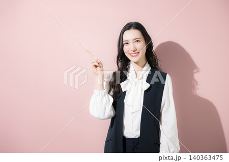 ピンク背景でガッツポーズをしながらカメラ目線で笑顔を見せる女性の成功と応援のイメージ 140363475