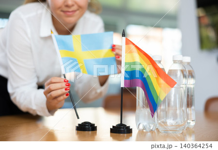 Unrecognizable girl sets midget flags of LGBT and Sweden before international negotiations Unrecognizable girl sets midget flags of LGBT and Sweden before international negotiations 140364254
