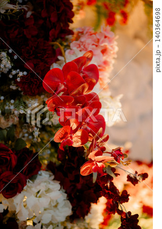 A stunning close-up view of a bright red orchid beautifully integrated into an elegant floral arrangement. 140364698