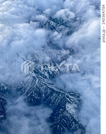 飛行機から俯瞰した雲の切れ間に広がる白銀の山岳地帯 飛行機から俯瞰した雲の切れ間に広がる白銀の山岳地帯 140364784