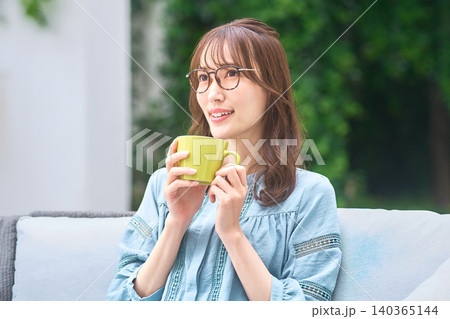 黄色いマグカップを手に明るく見上げる眼鏡の女性 140365144