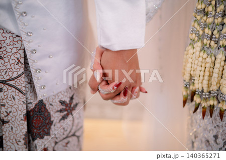 Traditional Javanese bridal couple hold hands as a symbol of love and commitment. 140365271