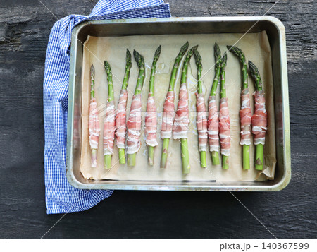 Prosciutto wrapped asparagus spears on a baking sheet	 140367599
