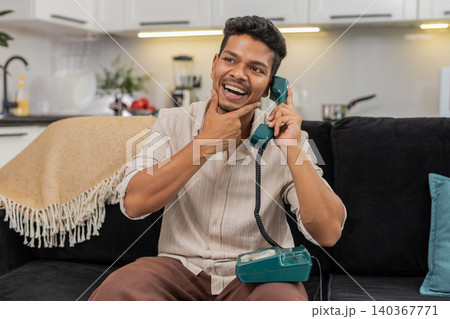 Indian man talks on retro corded phone nostalgic call listens and speaks with smile and gentle laugh 140367771
