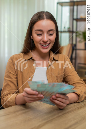 Young woman counting money hryvnia cash satisfied with salary earnings celebrating financial success Young woman counting money hryvnia cash satisfied with salary earnings celebrating financial success 140367953