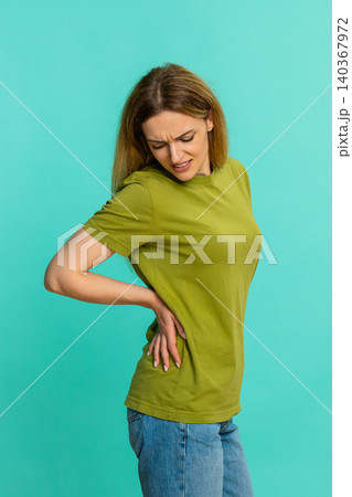 Woman holding lower back and straightening posture showing painful backache or spine muscle strain Woman holding lower back and straightening posture showing painful backache or spine muscle strain 140367972