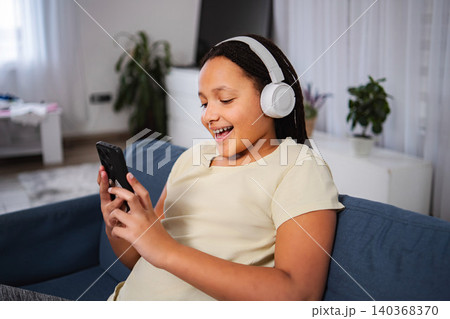 Young girl enjoying music and using smartphone with headphones Young girl enjoying music and using smartphone with headphones 140368370