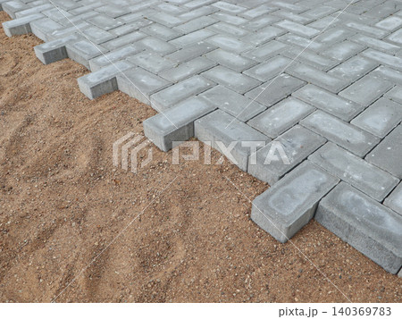 Paving the road from garden bricks by a professional paver. Laying gray concrete paving slabs on a gravel and sand base. 140369783
