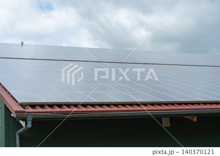 Angular close-up shot of a modern building roof equipped with photovoltaic solar panels. Represents eco-friendly home improvement, renewable power generation, and carbon footprint reduction. High 140370121