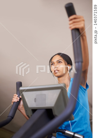 Woman, earphones and audio for cycling, bike and stationary machine for workout at club. Female person, cardio and inspirational podcast for motivation, playlist and equipment for fitness and health Woman, earphones and audio for cycling, bike and stationary machine for workout at club. Female person, cardio and inspirational podcast for motivation, playlist and equipment for fitness and health 140371589