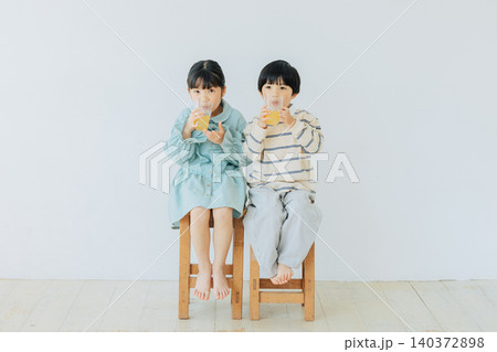 椅子に座ってジュースを飲む子ども 椅子に座ってジュースを飲む子ども 140372898