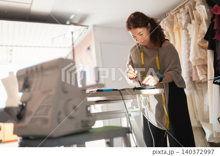 Female tailor creating fashion clothing in workshop 140372997