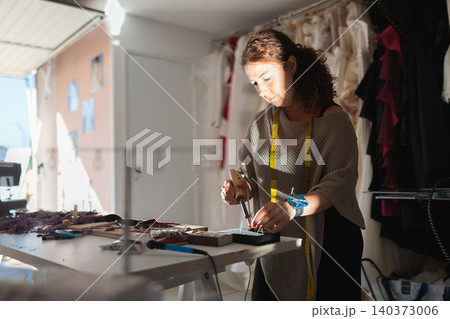 Craftswoman soldering details in fashion workshop creating design 140373006