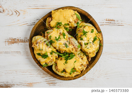 Baked potatoes with cheese and toppings in a wooden bowl placed on a table Baked potatoes with cheese and toppings in a wooden bowl placed on a table 140373380