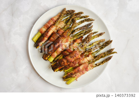 Bacon wrapped asparagus on white plate served as snack or side dish for lunch or dinner Bacon wrapped asparagus on white plate served as snack or side dish for lunch or dinner 140373392
