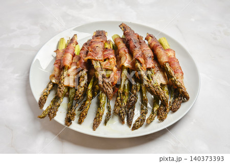 Bacon wrapped asparagus on white plate ready for serving at dinner time Bacon wrapped asparagus on white plate ready for serving at dinner time 140373393