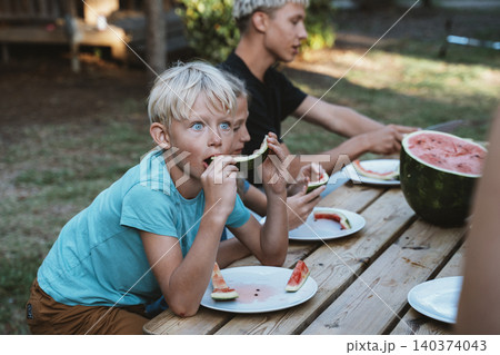 Children Enjoy Eating Watermelon at Picnic Table 140374043