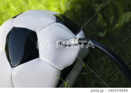 Inflating a soccer ball through a flexible hose with a needle, illustrating routine sports equipment maintenance and proper care. 140374044