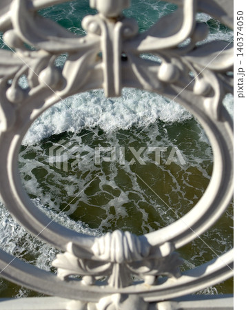 Churning Ocean Waves Through Ornate Cast Iron Railing Circular Medallion Coastal Churning Ocean Waves Through Ornate Cast Iron Railing Circular Medallion Coastal 140374050