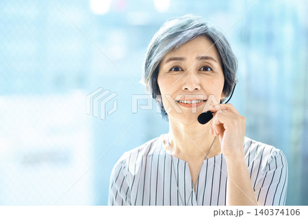 ヘッドセットを着けて笑顔で話すシニア女性 ヘッドセットを着けて笑顔で話すシニア女性 140374106