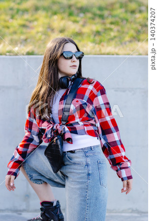 Stylish teenager posing wearing roller skates, sunglasses and headphones Stylish teenager posing wearing roller skates, sunglasses and headphones 140374207