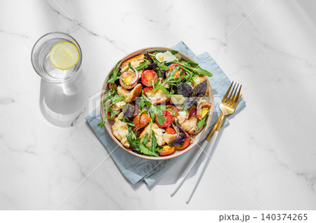 Tuscan panzanella salad with tomatoes, red onion, arugula, basil, cheese and bread in a bowl 140374265