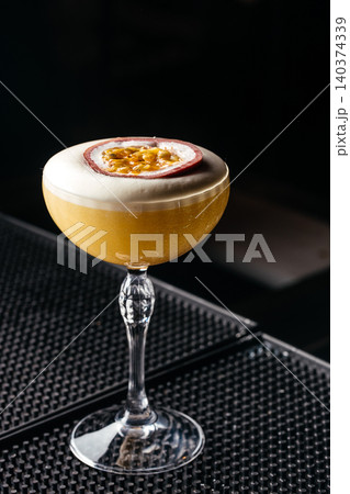 Exotic passion fruit cocktail in elegant coupe glass on dark bar counter 140374339