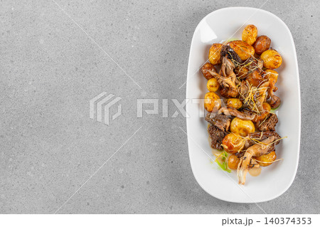 Roasted baby potatoes with wild mushrooms served on white plate over gray background 140374353
