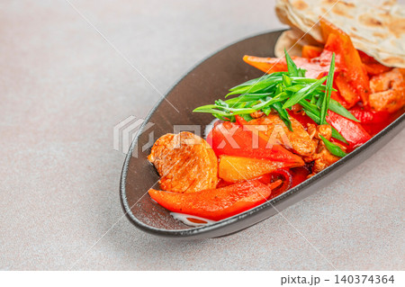 Stir Fried Meat with Bell Pepper and Flatbread on Black Plate 140374364