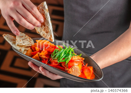 Chef Holding Spicy Meat Stir Fry with Vegetables and Flatbread Chef Holding Spicy Meat Stir Fry with Vegetables and Flatbread 140374366