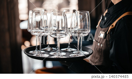 Waiter holding tray with empty wine glasses ready for service in restaurant 140374485