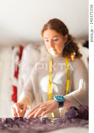 Craftswoman fashion designer working on garment in workshop Craftswoman fashion designer working on garment in workshop 140375356