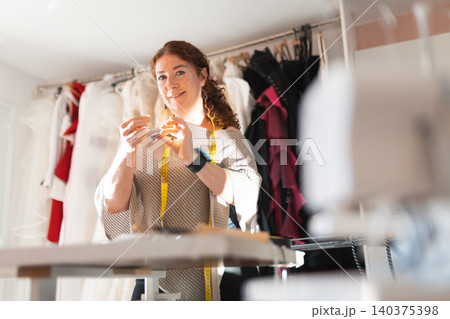 Female tailor creating fabric item in design studio Female tailor creating fabric item in design studio 140375398