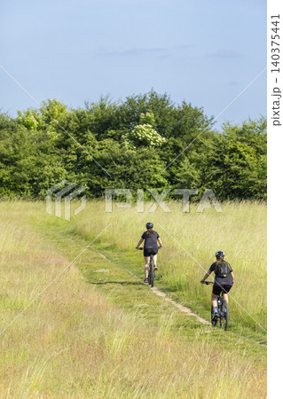 Women cycling on dirt path in Hostivice meadow Women cycling on dirt path in Hostivice meadow 140375441