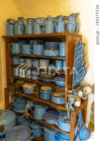 Vintage blue enamel kitchenware collection on wooden shelves 140375538