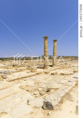 Two ancient Roman columns standing under a clear blue sky amidst ruins Two ancient Roman columns standing under a clear blue sky amidst ruins 140375606