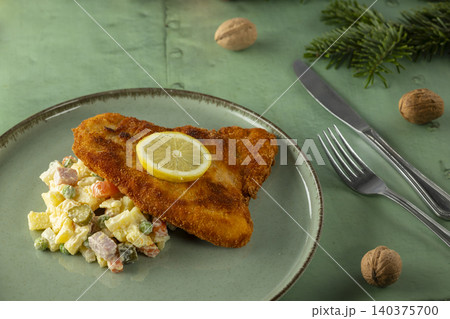 Crispy schnitzel with traditional potato salad and lemon Crispy schnitzel with traditional potato salad and lemon 140375700