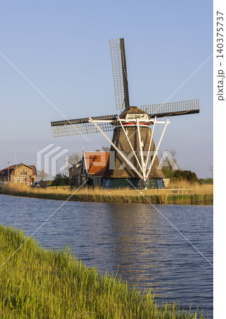Dutch windmill standing by canal in Heerhugowaard, Netherlands Dutch windmill standing by canal in Heerhugowaard, Netherlands 140375737