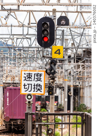 鉄道の信号機と速度切換の標識と通過していく車両のある風景(縦構図・圧縮効果) 鉄道の信号機と速度切換の標識と通過していく車両のある風景(縦構図・圧縮効果) 140376082