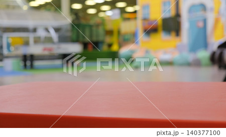Empty red surface in front of blurred child colorful playroom with toys for marketing presentation. Table for product placement with blurred kindergarten or baby room background. Nursery backdrop. Empty red surface in front of blurred child colorful playroom with toys for marketing presentation. Table for product placement with blurred kindergarten or baby room background. Nursery backdrop. 140377100