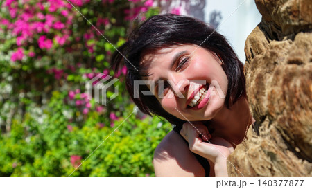 Woman's portrait against a vibrant floral wall background with soft natural lighting Woman's portrait against a vibrant floral wall background with soft natural lighting 140377877