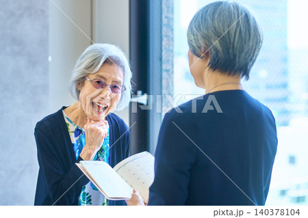 資料を見せながら話す笑顔のシニア女性 資料を見せながら話す笑顔のシニア女性 140378104