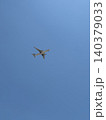 White Jet Airliner Flying High Overhead Seen From Ground Against Blue Sky 140379033
