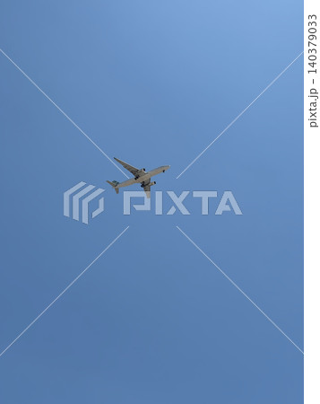 White Jet Airliner Flying High Overhead Seen From Ground Against Blue Sky White Jet Airliner Flying High Overhead Seen From Ground Against Blue Sky 140379033