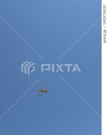 Distant Airplane Tiny Silhouette Against Large Expanse of Clear Blue Sky Distant Airplane Tiny Silhouette Against Large Expanse of Clear Blue Sky 140379035