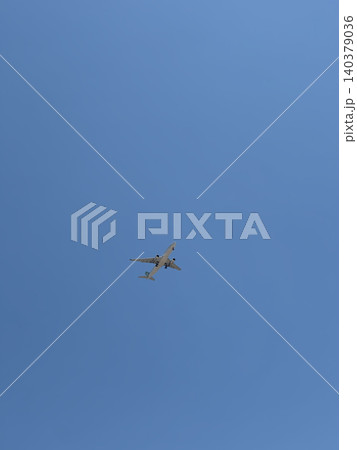 Commercial Airliner Flying Overhead in Clear Blue Sky With Lots of Open Space 140379036
